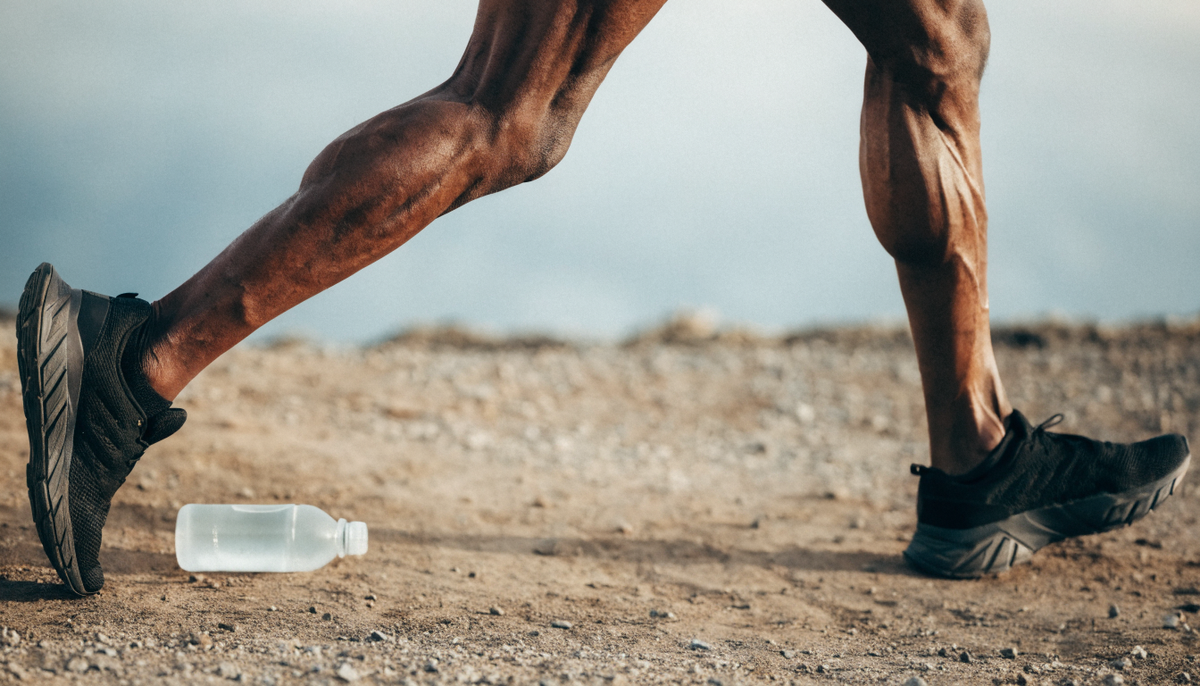 Sportif en trail avec bouteille d'hydratation pour prevenir les crampes musculaires