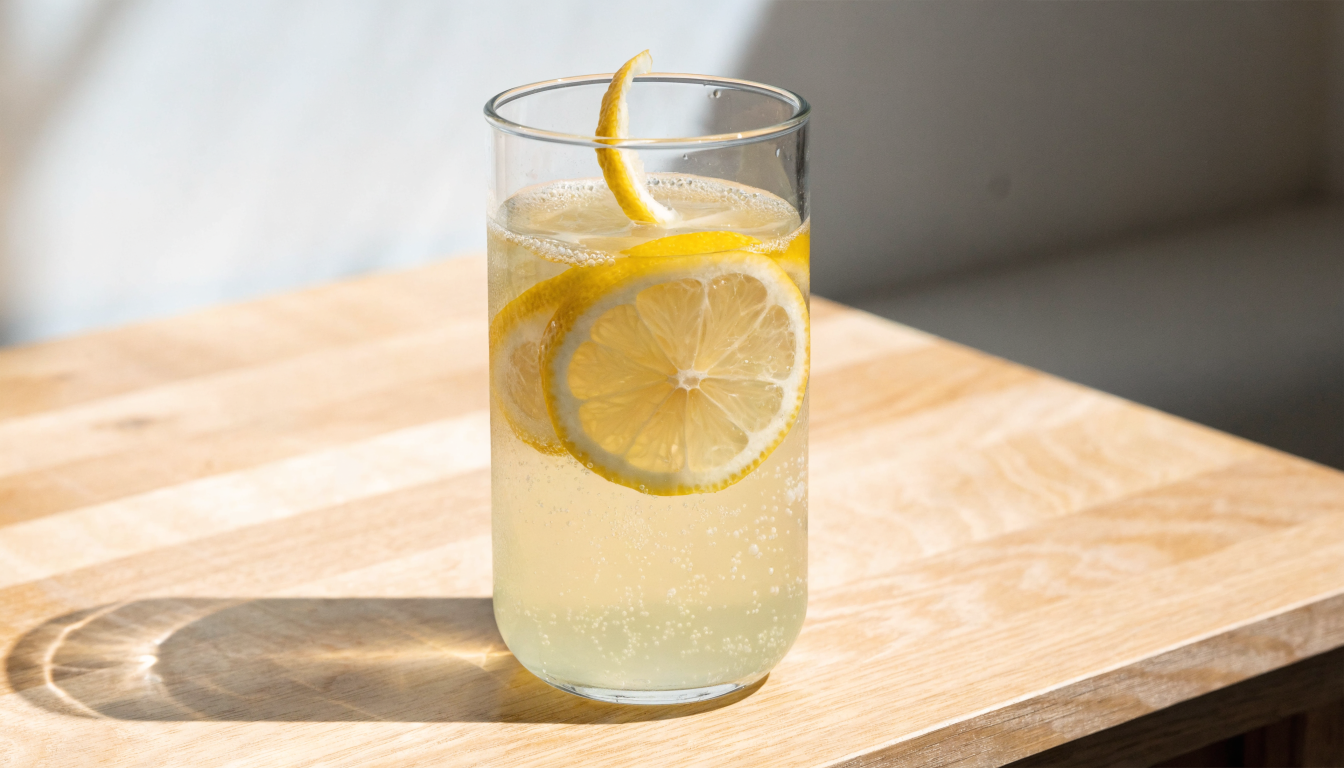 Verre de boisson électrolytes maison avec citron et sel de mer sur une table en bois clair